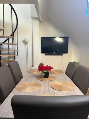 a dining room table with chairs and a television at littoral in Brussels