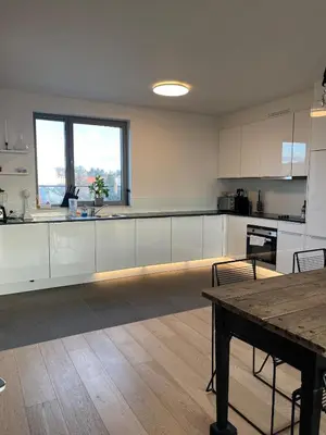 a kitchen with white cabinets and a wooden table at Refined apartment with terraces in Brussels