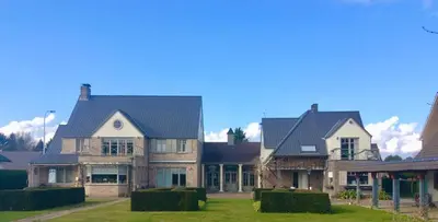 a large house with a roof on a green yard at De Loft in Melsele