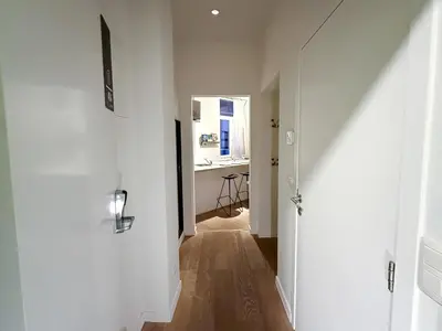 a hallway with white walls and a door with a sink at Studio 204 cosy au centre de Bruxelles in Brussels