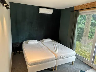 a bedroom with two beds and a green wall at Woodboxcabins - Campinggroenpark in Zele