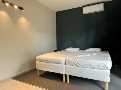 a white bed in a room with a green wall at Woodboxcabins - Campinggroenpark in Zele