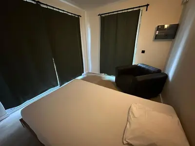 a bedroom with a bed and a chair and a window at Woodboxcabins - Campinggroenpark in Zele