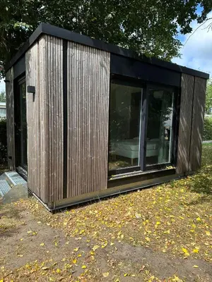 a small wooden building with windows in a yard at Woodboxcabins - Campinggroenpark in Zele