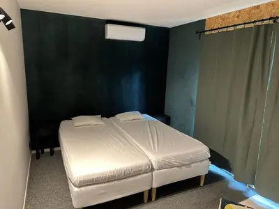 a white bed in a room with a green wall at Woodboxcabins - Campinggroenpark in Zele