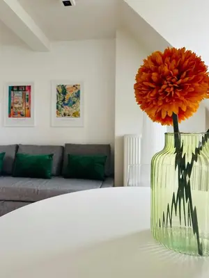 a vase with a large orange flower in a living room at The Central Experience - 2 BR, Bright, Spacious & Central in Brussels
