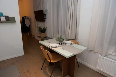a room with a table with chairs and a television at Studio 1 Cosy Avenue Louise in Brussels