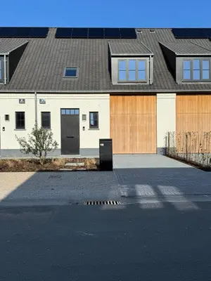 a house with two garage doors and a driveway at Maison frère in Berlare