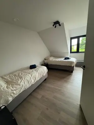 two beds in a small room with a wooden floor at Maison frère in Berlare