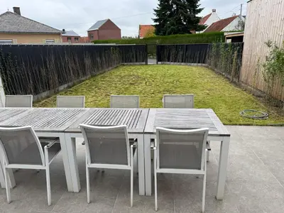 a wooden table and chairs in a backyard at Maison frère in Berlare