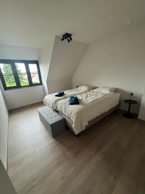 a bedroom with a large bed and two windows at Maison frère in Berlare