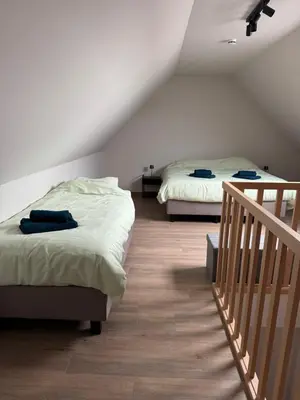 two beds in a room with a staircase and a room with two beds at Maison frère in Berlare