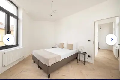 a white bedroom with a large bed and a window at Groot rustgevend huis met dakterras uitzicht op het groen kwartier van Berchem in Antwerp