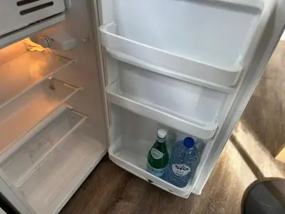an open refrigerator with two bottles of water in it at Cozy 1BR & Living Room Apartment, Just 15 Minutes to Downtown in Ghent