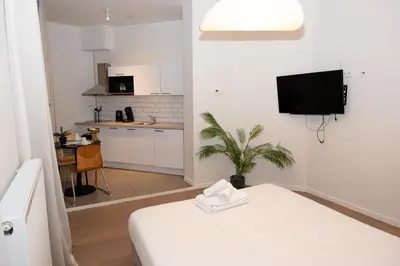 a white room with a bed and a kitchen at Studio 402 Avenue Louise in Brussels