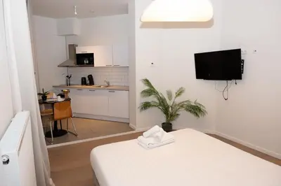 a white room with a bed and a kitchen at Studio 402 Avenue Louise in Brussels