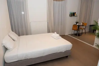 a bedroom with a bed with white sheets and a table at Studio 402 Avenue Louise in Brussels