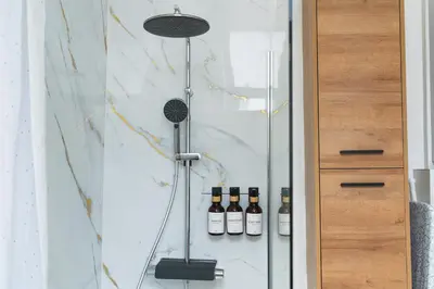 a glass shower with bottles of wine in it at Lovely 1BR & 1LR Apartment, Only 15 Min Walk to City Center in Ghent
