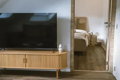 a flat screen tv sitting on top of a wooden dresser at Cozy 1BR & Living Room Apartment, Just 15 Minutes to Downtown in Ghent