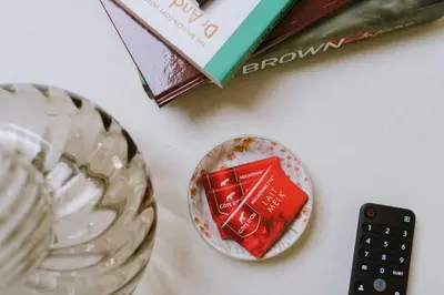 a table with a book and a bowl of food and a remote control at Cozy 1BR & Living Room Apartment, Just 15 Minutes to Downtown in Ghent