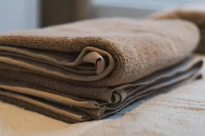 a stack of brown towels sitting on top of a bed at Cozy 1BR & Living Room Apartment, Just 15 Minutes to Downtown in Ghent
