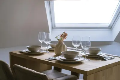 a wooden table with plates and wine glasses on it at Cozy 1BR & Living Room Apartment, Just 15 Minutes to Downtown in Ghent
