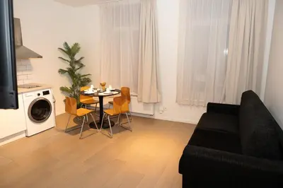 a living room with a black couch and a table with chairs at Studio 003 Avenue Louise in Brussels