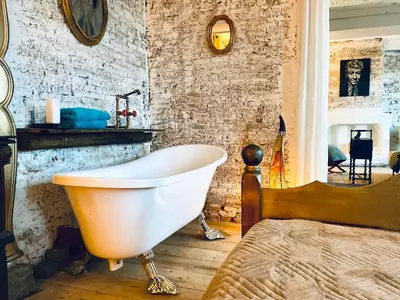 a bathroom with a white bath tub next to a bed at Legions Suite in Antwerp