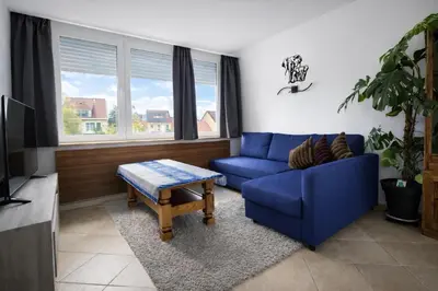 a living room with a blue couch and a table at cozy studio Brussels airport in Steenokkerzeel