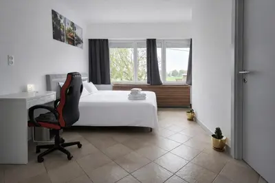 a bedroom with a bed and a desk and a chair at cozy studio Brussels airport in Steenokkerzeel