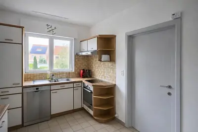 a kitchen with white cabinets and a sink and a window at cozy studio Brussels airport in Steenokkerzeel