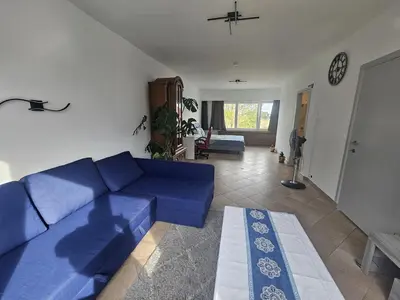 a living room with a blue couch and a table at cozy studio Brussels airport in Steenokkerzeel
