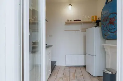 a kitchen with a white refrigerator and a wooden floor at Urban Hideout Just Steps from Antwerp's Highlights in Antwerp