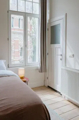 a bedroom with a bed and a large window at Urban Hideout Just Steps from Antwerp's Highlights in Antwerp