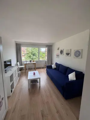 a living room with a blue couch and a table at Studio Blueberry in Brussels