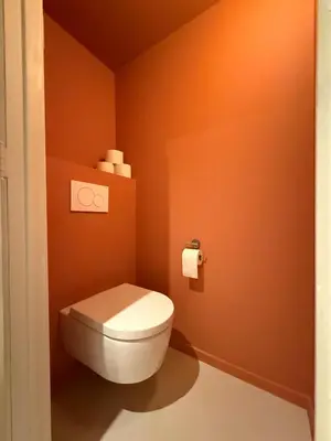 a bathroom with a white toilet in an orange wall at European Smart Studio in Brussels