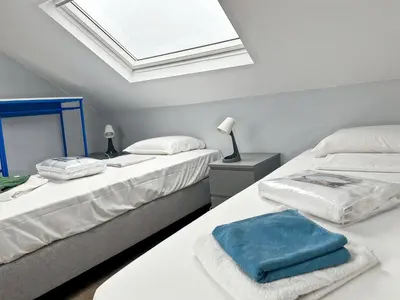 two beds in a white room with a window at Charming Entire Apartment in Saint-Gilles, Brussels in Brussels
