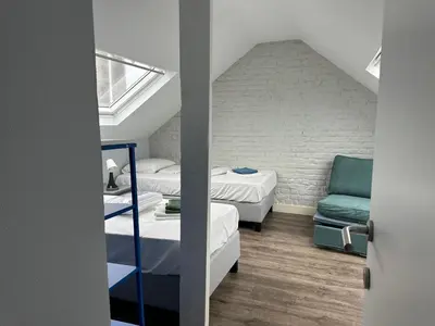 a room with two beds and a blue chair at Charming Entire Apartment in Saint-Gilles, Brussels in Brussels