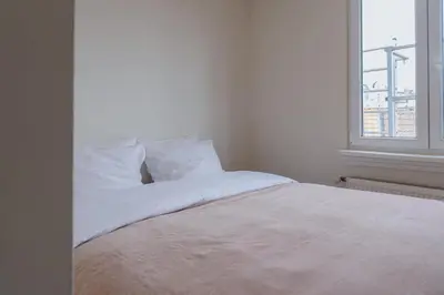 a white bed in a room with a window at Cozy Apartment in Central Antwerp in Antwerp