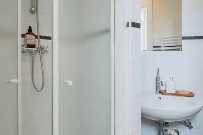 a white bathroom with a sink and a shower at Cozy Hideaway Near the Heart of Antwerp in Antwerp