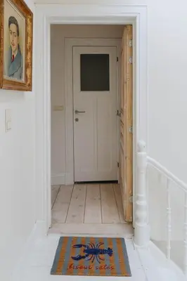 a hallway with a white door and a rug at Cozy Hideaway Near the Heart of Antwerp in Antwerp