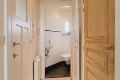 a bathroom with a toilet and a wooden door at Cozy Hideaway Near the Heart of Antwerp in Antwerp