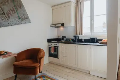 a kitchen with white cabinets and a chair and a stove at Cozy Hideaway Near the Heart of Antwerp in Antwerp