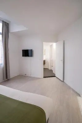 a white room with a bed and a flat screen tv at Mérode 3 in Brussels
