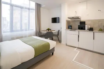 a bedroom with a bed and a kitchen with a table at Jourdan 4 in Brussels