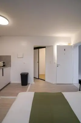 a room with white walls and a bed with a green blanket at Jourdan 4 in Brussels