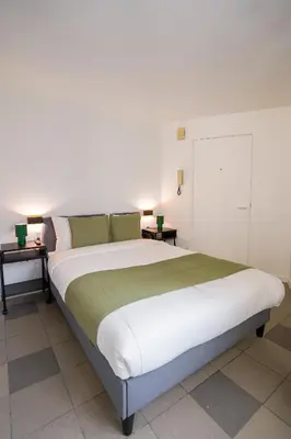 a large bed in a room with two tables at La Chasse 5 in Brussels