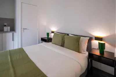 a bedroom with a large white bed with two lamps at La Chasse 5 in Brussels