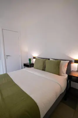 a bedroom with a large white bed with two tables at La Chasse 5 in Brussels