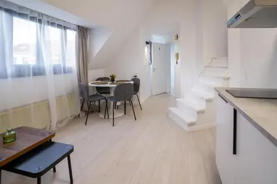 a white apartment with a table and chairs and stairs at Luxembourg 6 in Brussels